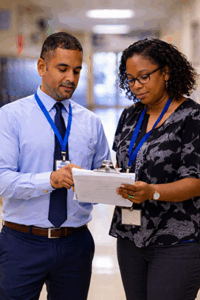 Two school staff members looking at a clipboard.